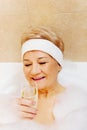 Senior Woman Relaxing In Bath With Glass Of Champagne