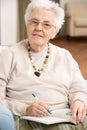 Senior Woman Relaxing In Chair At Home Royalty Free Stock Photo