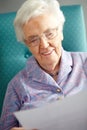 Senior Woman Relaxing In Chair Reading Letter Royalty Free Stock Photo