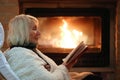 Senior woman relaxing by fireplace Royalty Free Stock Photo