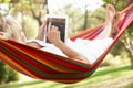 Senior Woman Relaxing In Hammock With E-Book Royalty Free Stock Photo