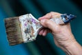 Senior woman right hand holding old paintbrush in bokeh blue swimming pool background, Selective focus, Hobby paint art concept Royalty Free Stock Photo