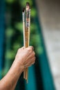 Senior woman right hand holding old paintbrushes in bokeh blue swimming pool background, Selective focus, Hobby paint art concept Royalty Free Stock Photo