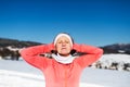 Senior woman runner resting in winter nature, eyes closed and hands behind head.