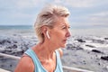 Senior woman running at beach with earphones for energy, wellness or healthy workout. Elderly female, exercise and Royalty Free Stock Photo