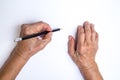 Senior woman`s hand with black pencil writing on white paper