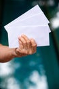 Senior woman left hand holding 2 white envelopes in bokeh blue swimming pool background, Close up shot, Business concept Royalty Free Stock Photo
