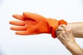 Senior woman hands wearing orange rubber protective glove in white background, Close up shot, Prevention from covid19