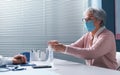 Senior woman sanitizing her hands in the doctor`s office