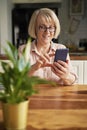 Senior woman scrolling on the phone at home