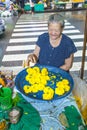 senior woman sells orange holy flowers to the local people at the night market Pak khlong Talat in Chinatown, Bangkok