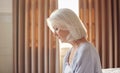 Senior Woman With Serious Expression Sitting On Edge Of Bed At Home During Lockdown For Covid-19 Royalty Free Stock Photo