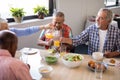 Senior woman serving drink to friends at table Royalty Free Stock Photo