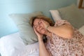 Senior woman with severe headache lying on the bed in her room Royalty Free Stock Photo