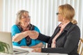 Senior Woman Shaking Hands with Businesswoman Near Laptop Computer