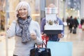 Senior Woman Shopping In Mall As Husband Carries Boxes Royalty Free Stock Photo