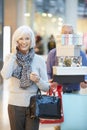 Senior Woman Shopping In Mall As Husband Carries Boxes Royalty Free Stock Photo