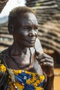 BOYA TRIBE, SOUTH SUDAN - MARCH 10, 2020: Senior woman with short hair carrying knife on shoulder and looking away on blurred