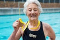 Senior woman showing gold medal at poolside Royalty Free Stock Photo