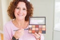 Senior woman showing nudes eyeshadows colors with a happy face standing and smiling with a confident smile showing teeth