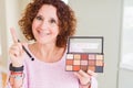 Senior woman showing nudes eyeshadows colors surprised with an idea or question pointing finger with happy face, number one