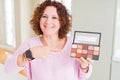 Senior woman showing nudes eyeshadows colors very happy pointing with hand and finger