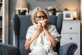 Senior woman sick and blowing nose at home from virus, allergy and illness on couch. Tired, tissue and elderly female person in a Royalty Free Stock Photo