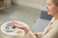 Senior woman sit on couch having daily vitamins or diet supplements at home, mature old female pensioner take dose of pills from Royalty Free Stock Photo