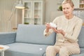 Senior woman sit on couch having daily vitamins or diet supplements at home, mature old female pensioner take dose of pills from Royalty Free Stock Photo