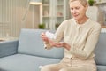 Senior woman sit on couch having daily vitamins or diet supplements at home, mature old female pensioner take dose of pills from Royalty Free Stock Photo