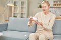 Senior woman sit on couch having daily vitamins or diet supplements at home, mature old female pensioner take dose of Royalty Free Stock Photo