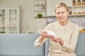 Senior woman sit on couch having daily vitamins or diet supplements at home, mature old female pensioner take dose of pills from Royalty Free Stock Photo