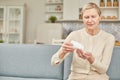 Senior woman sit on couch having daily vitamins or diet supplements at home, mature old female pensioner take dose of pills from Royalty Free Stock Photo