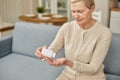 Senior woman sit on couch having daily vitamins or diet supplements at home, mature old female pensioner take dose of Royalty Free Stock Photo