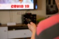 A senior woman sits in front of the television watching television. She holds a remote control in her hand that she points at the Royalty Free Stock Photo