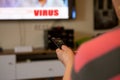 A senior woman sits in front of the television watching television. She holds a remote control in her hand that she points at the Royalty Free Stock Photo