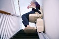 Senior Woman Sitting On Stair Lift At Home To Help Mobility Royalty Free Stock Photo