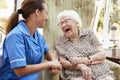 Senior Woman Sitting In Chair And Laughing With Nurse In Retirement Home Royalty Free Stock Photo