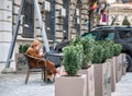 Senior woman sitting on a chair and smoking a cigar or a cigarette in the center of Bucharest