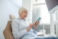 Senior woman sitting at the dentists office and using her smartphone Royalty Free Stock Photo