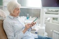 Senior woman sitting at the dentists office and using her smartphone Royalty Free Stock Photo