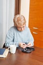 Senior woman sitting at the desk and cutting fingers nails Royalty Free Stock Photo