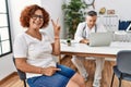 Senior woman sitting at doctor appointment smiling with happy face winking at the camera doing victory sign Royalty Free Stock Photo