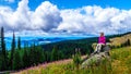 Senior woman sitting on a large rock in the alpine meadows covered in wildflowers Royalty Free Stock Photo