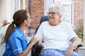 Senior Woman Sitting In Motorized Wheelchair Talking With Nurse In Retirement Home Royalty Free Stock Photo