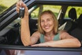 Senior woman sitting in new car outdoors holding keys, smiling, enjoying journey. Driving courses and life insurance Royalty Free Stock Photo
