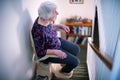 Senior Woman Sitting On Stair Lift At Home To Help Mobility