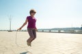 Senior woman with skipping rope doing practice in a public park in the center of town. Royalty Free Stock Photo