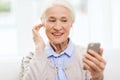 Senior woman with smartphone and earphones at home Royalty Free Stock Photo