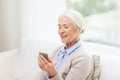 Senior woman with smartphone and earphones at home Royalty Free Stock Photo